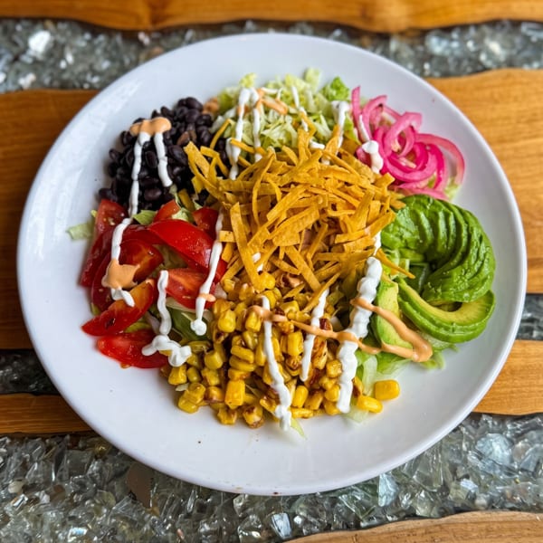 Fresh taco salad with black beans, corn, avocado, tomatoes, pickled onions, and tortilla strips.