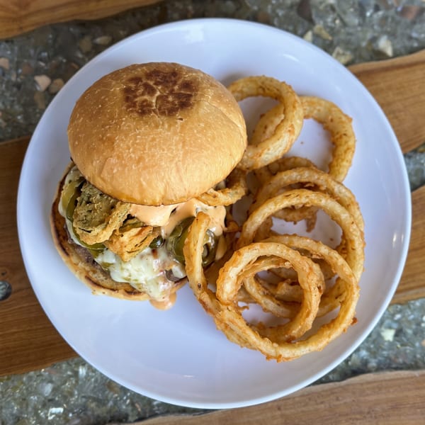 Cheeseburger with melted cheese, jalapeños, crispy fried onions, and sauce, served with golden onion rings.